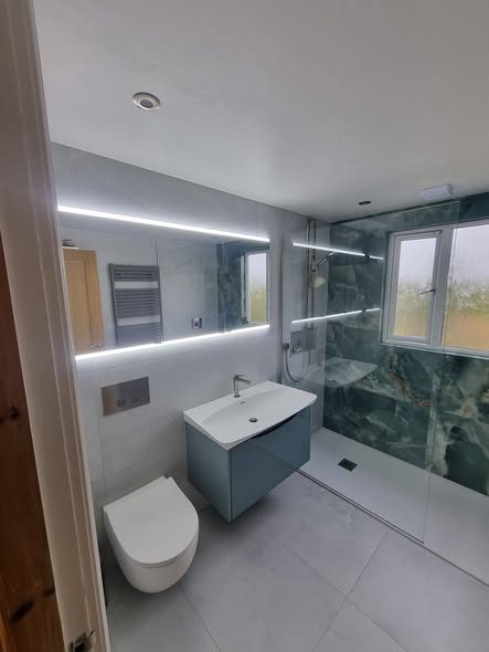 Finished bathroom by Lawrence Plumbing & Gas: green marble-effect shower, wall-hung vanity and LED mirror